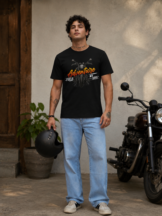 Male model wearing black Adventure Fuels My Soul Premium Biker T-Shirt standing beside a motorcycle.