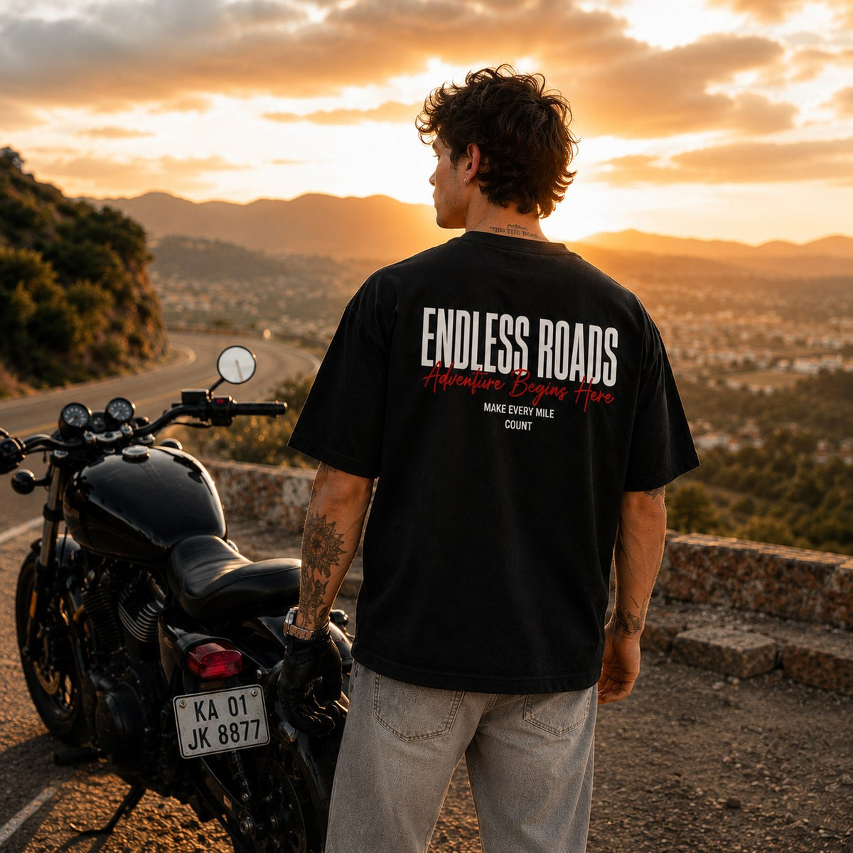 Rider in black Endless Roads oversized biker t-shirt on a mountain highway at sunset.