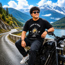 Male rider wearing the black Finding My North premium biker T-shirt beside a motorcycle on a scenic mountain road.